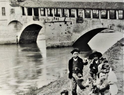 La riva del Ticino e dietro il Ponte Coperto: scena ideale a Pavia per una foto di bambini di fine '800